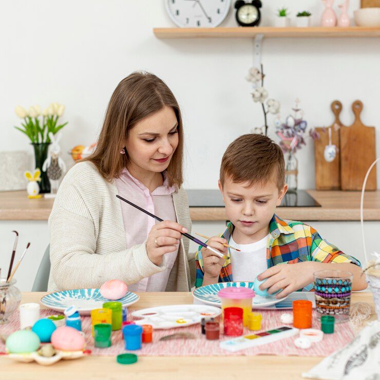 High angle mom helping son to paint eggs